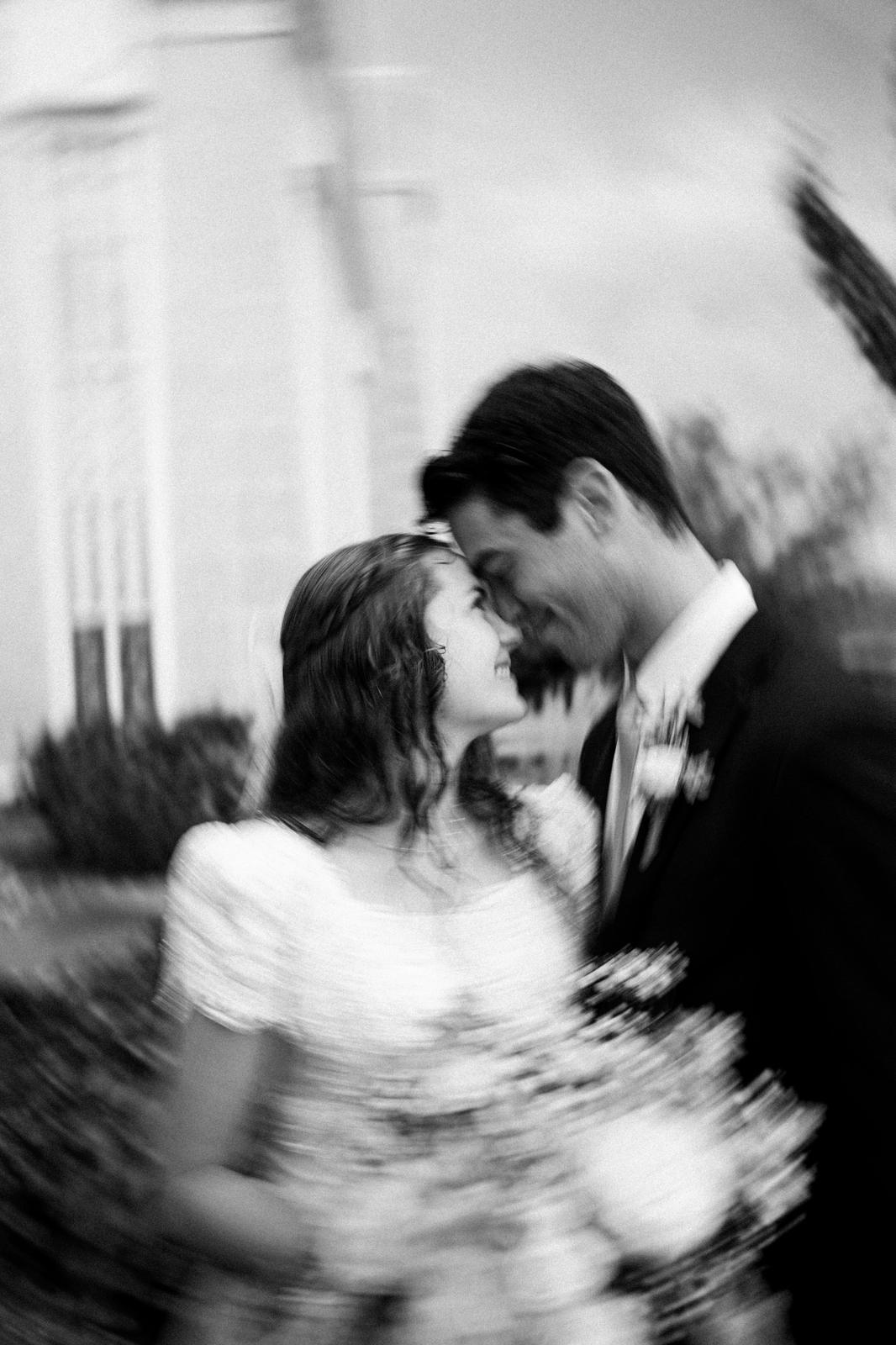 Bride and groom forehead to forehead, black and white with motion blur